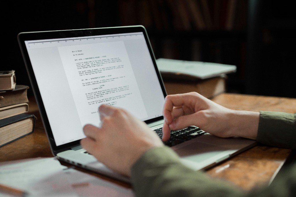 Screenplay open on a laptop — rewriting and formatting in progress